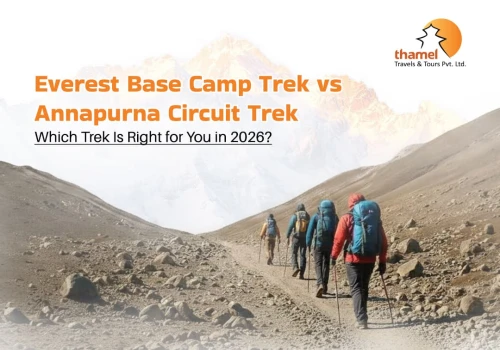 Trekker standing at the Everest Base Camp rock marker with colorful prayer flags and the Khumbu Icefall in the background.